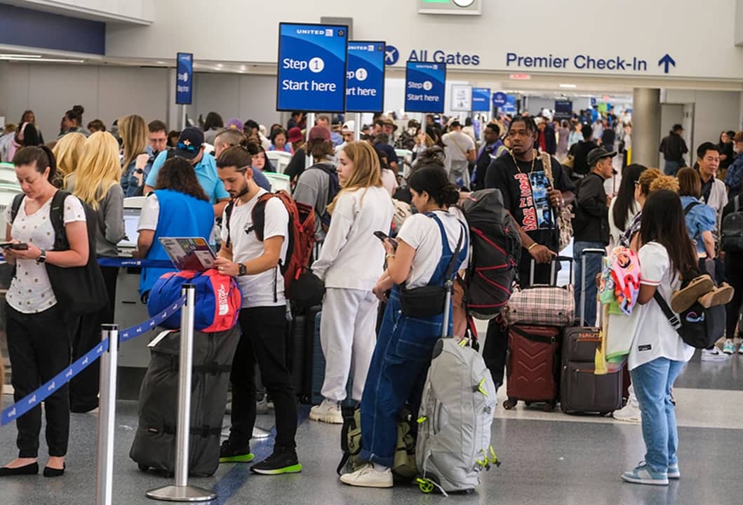 Travelers waiting in line before the check-in counters at an international airport.